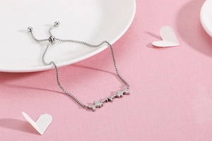 Detail of stainless steel bracelet with fish motif on a textured pink background