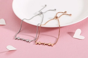 Detail of adjustable fish and heartbeat charms bracelets in silver and rose gold