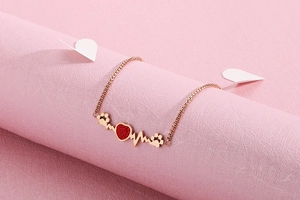Detailed view of heart-shaped red diamond and paw print on rose gold titanium bracelet