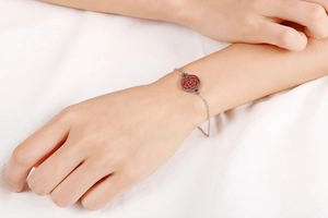 Gros plan détaillé d'un bracelet argenté avec pendentif rose évidé sur un poignet
