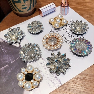 Exquisite crystal flower phone grips with pearls and rhinestones on a desk