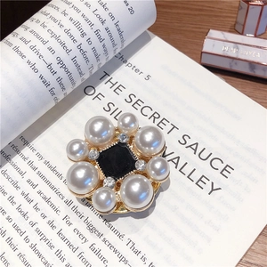 Macro shot of a vintage floral pearl brooch with black enamel on an open book