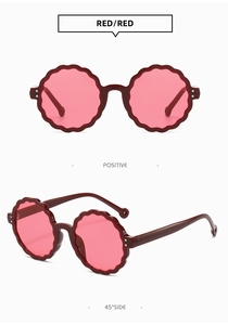 Detail view of red petal-shaped round children's sunglasses with UV protection features