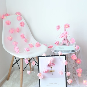 Pink rose LED string lights with warm white glow draped over white home furniture