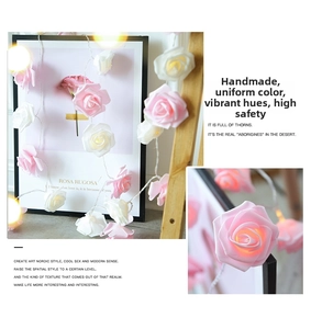 Detail of pink and white LED rose flower string lights with warm glowing petals