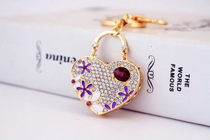 Detail of heart keychain with rhinestones, purple flower petals and a large red gemstone