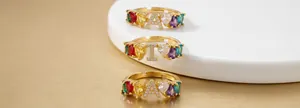 Detailed view of rainbow zircon letter rings with M I A charms in golden finish