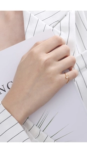 Detail of a minimalist adjustable gold meteor ring with a single zircon on a model's hand