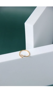 Macro shot of a thin gold minimalist ring with a single round zircon on a white stand