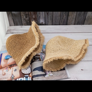 Detailed close-up of straw hats with fringe edges in dark brown and light beige color