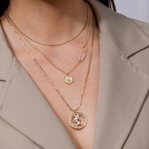 Detailed view of triple-layered gold necklace with coin pendants and pearl accents