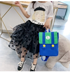 Detail of a kids' color-block backpack with letter L logo and cute graphic tee outfit