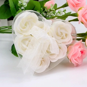 Close-up of 6 white soap roses in a heart-shaped transparent gift box with a white ribbon