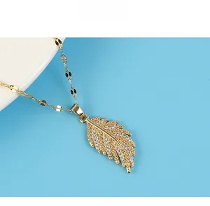Macro shot of 18K gold-plated feather pendant necklace featuring sparkling zircon inlay