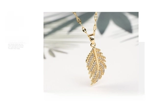 Detailed close-up of a gold feather pendant necklace featuring sparkling zircon inlay
