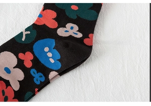 Macro detail of black cotton socks featuring colorful knitted floral and cloud patterns