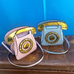 Detail of retro telephone shaped crossbody bags in pink and light blue with gold sequins