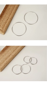 Close-up of minimalist S925 sterling silver hoop earrings in various sizes on wood
