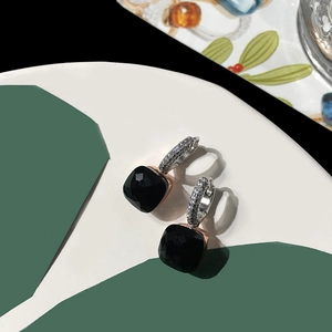 Detail of square-cut black gemstone earrings with silver micro-pave setting on bicolor backdrop