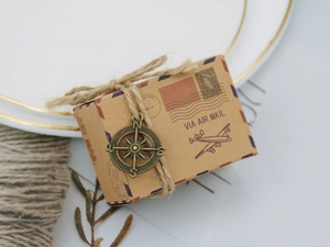 Detail of vintage kraft paper candy box with twine and a bronze compass alloy charm