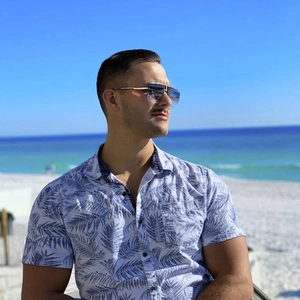 Close-up of rimless gradient aviator sunglasses worn by a model on a sunny beach