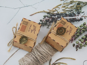 Detail of vintage kraft paper candy box with compass charm and rustic twine cord
