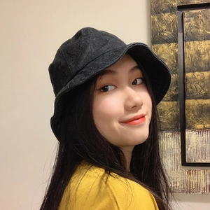 Detail view of black denim bucket hat stitching and brim shown on female model