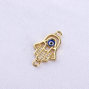 Macro detail of gold-plated Hamsa Hand connector with pavé zircon and blue evil eye
