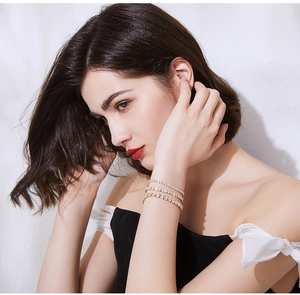 Close-up of a three-layered gold tennis bracelet with cubic zirconia on a model's wrist