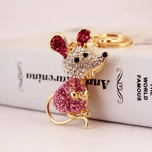 Porte-clés souris mignon avec cristaux roses sur base dorée posé sur un livre ancien