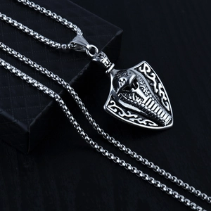 Gros plan détaillé du pendentif bouclier cobra argenté avec textures tribales sur coffret