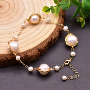 Close-up of handmade freshwater pearl bracelet with gold wire wrap on a wood surface