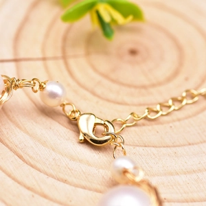 Handmade freshwater pearl bracelet with gold wire wrapping and lobster clasp on wood
