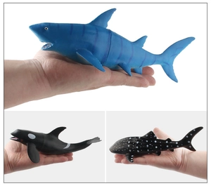 Detailed comparison of realistic shark and whale toys with hand for scale reference