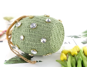 Detail of light green straw bucket bag with large rhinestones and woven handles
