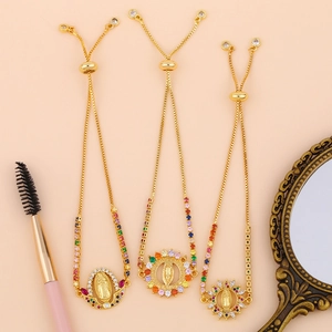 Detail of adjustable gold bracelets set with colorful zircons and Virgin Mary pendants