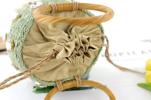 Detail view of light green straw bucket bag with rhinestone accents and wooden handles