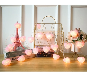 Pink heart LED string lights on a wooden desk with decorative romantic props