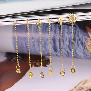 Macro detail of six gold-plated long tassel earrings with snake and star charms