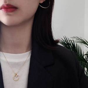 Close-up of a model wearing a gold S925 silver moon and pearl necklace with hoop earrings