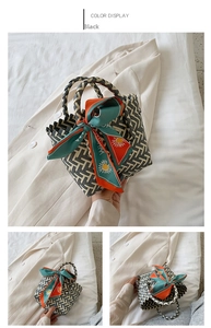 Détail d'un sac à main tissé noir et blanc avec un foulard en soie floral sur l'anse