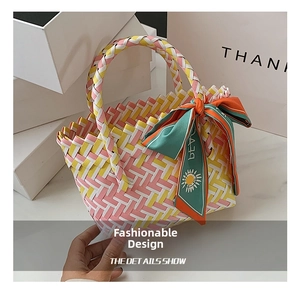 Detail of woven basket bag in pink yellow and white with a floral silk scarf handle