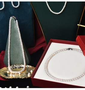 Macro shot of white freshwater pearl necklaces and loose beads in high-end gift packaging