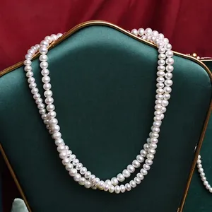 Elegant double-layer white freshwater pearl necklace displayed on a green jewelry stand