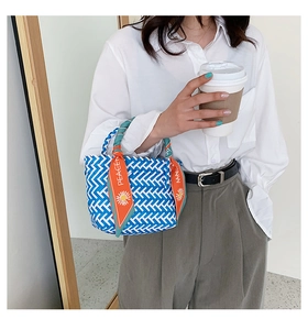 Détail d'un sac à main tissé bleu et blanc avec un foulard en soie décoratif sur l'anse
