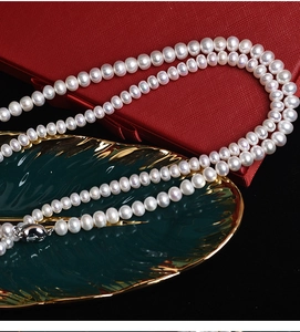 Detailed view of genuine white freshwater pearl necklace on luxury red jewelry gift box