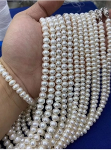 Close-up of hand holding glossy white freshwater pearl necklace with natural luster