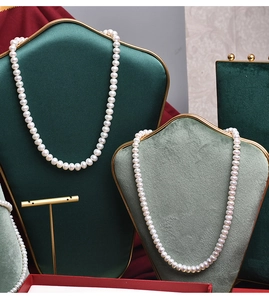 Detailed view of genuine white round pearl necklaces on elegant velvet jewelry displays
