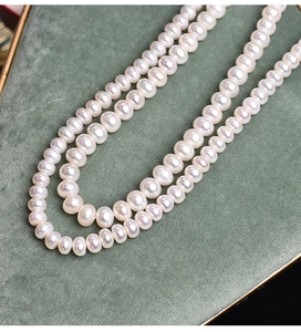 Detailed close-up of high-luster white round freshwater pearls on dark green velvet