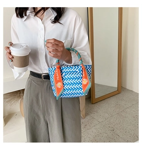 Détail du sac à main tissé bleu et blanc avec une poignée décorative en soie orange